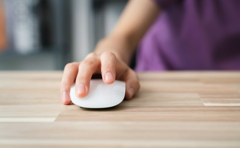 Close up of hand using on white mouse and clicking on office table.